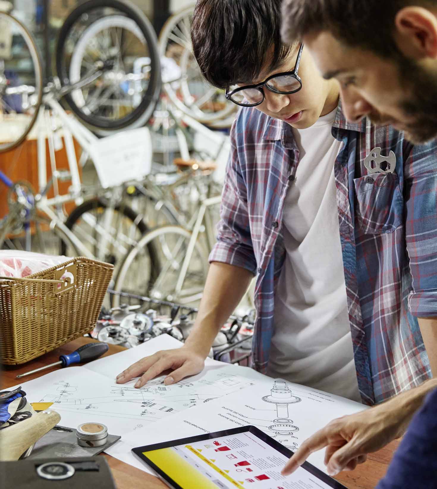 Two partners of a bicycle specialist business discussing e-commerce solutions in their workshop.