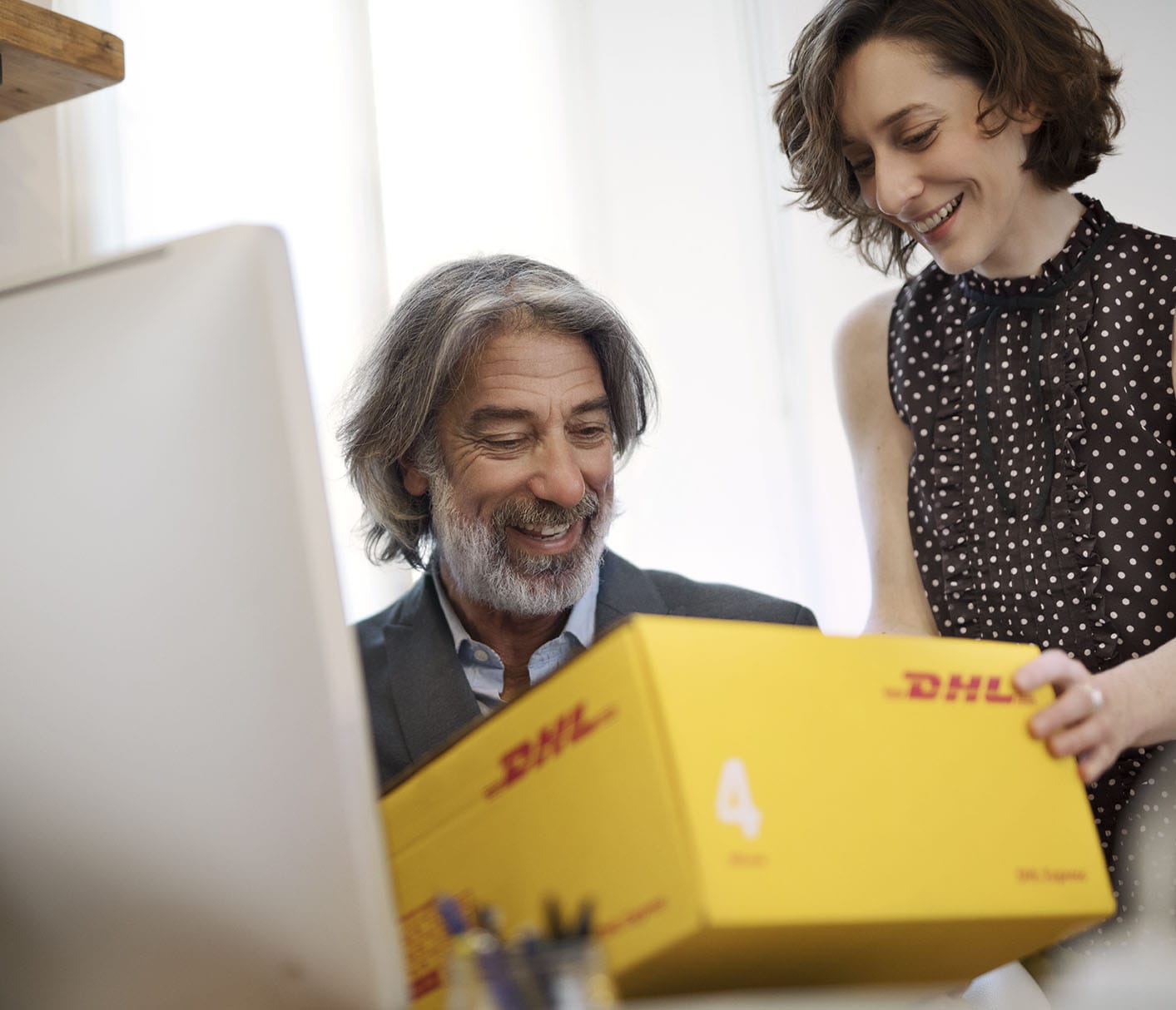 A couple preparing a DHL parcel in front of a computer for international shipment.
